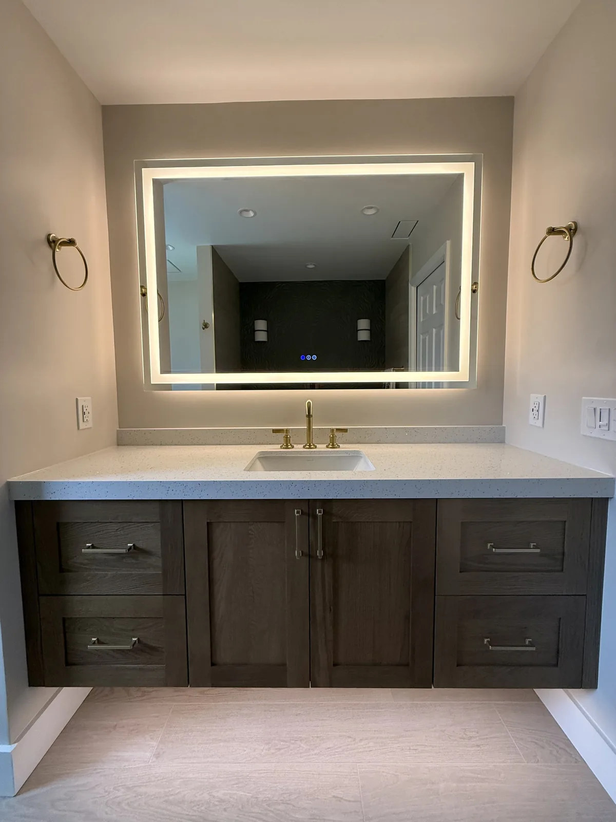 Bathroom vanity remodel with dark wood cabinetry and a backlit LED mirror in Central Florida
