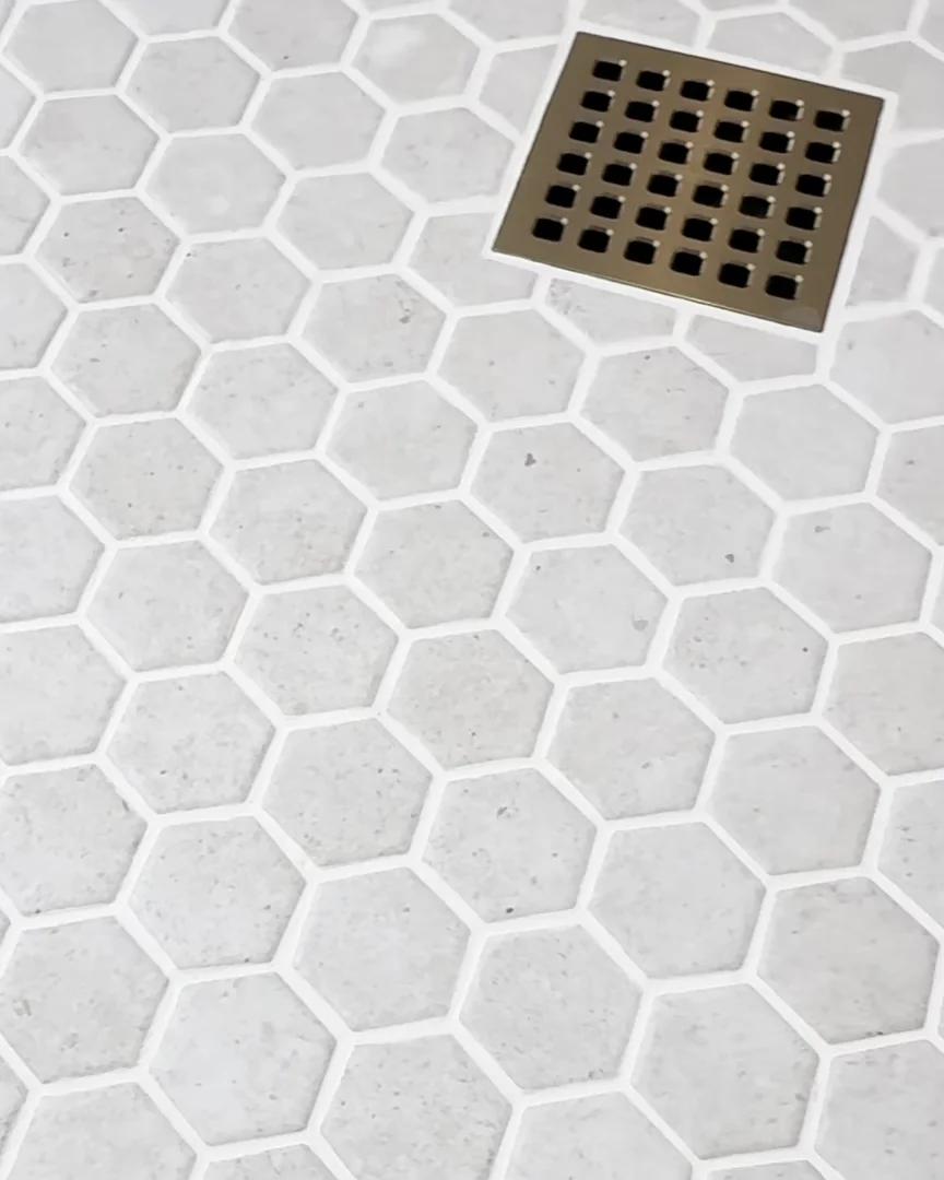 Hexagon tile shower floor with a square brass drain in a Dr. Phillips, Orlando bathroom remodel