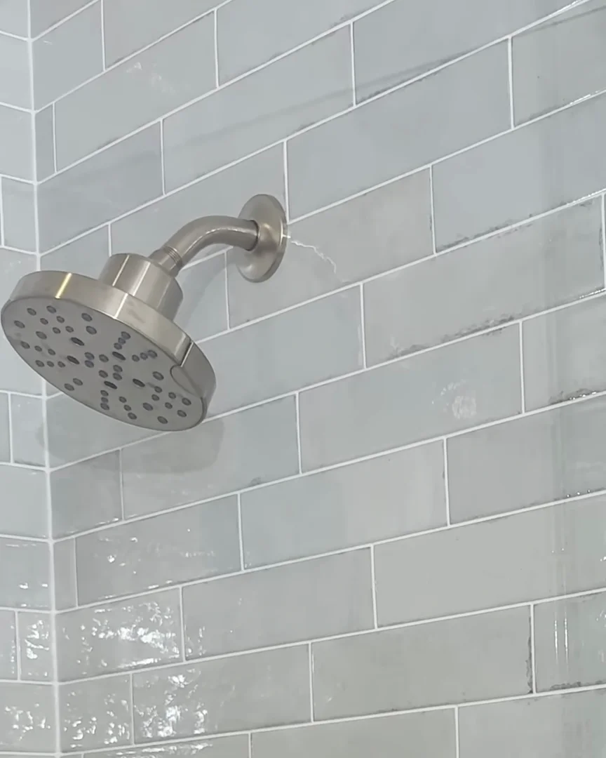 Shower head on glossy pale green tile in a Dr. Phillips, Orlando walk-in shower remodel