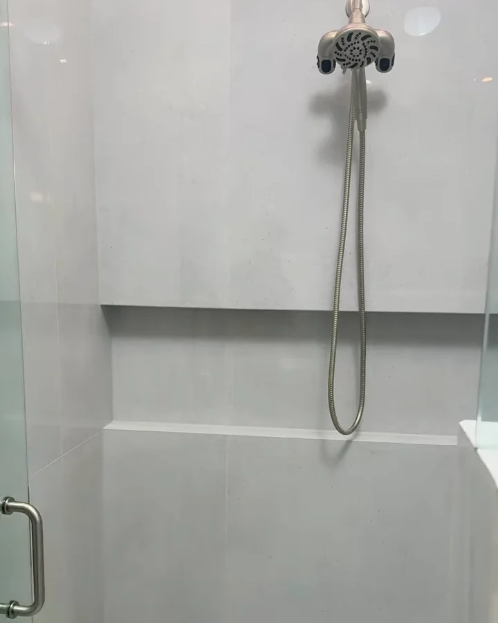 Curbless walk-in shower with large-format gloss tile, a mitered infinity niche and a handheld shower in Sorrento, FL