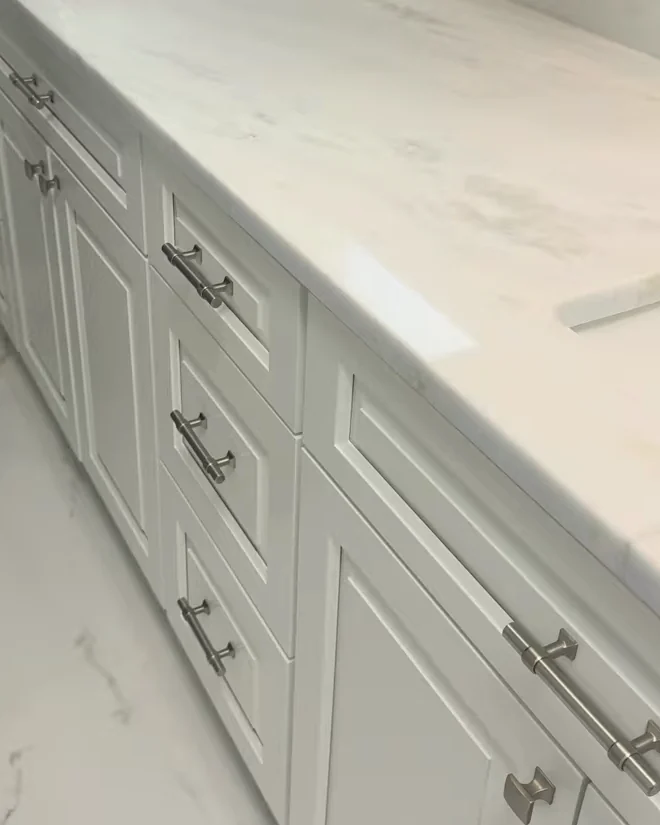 White vanity with drawer bases, satin-finish pulls and a marble-look countertop in a Sorrento, FL master bathroom remodel