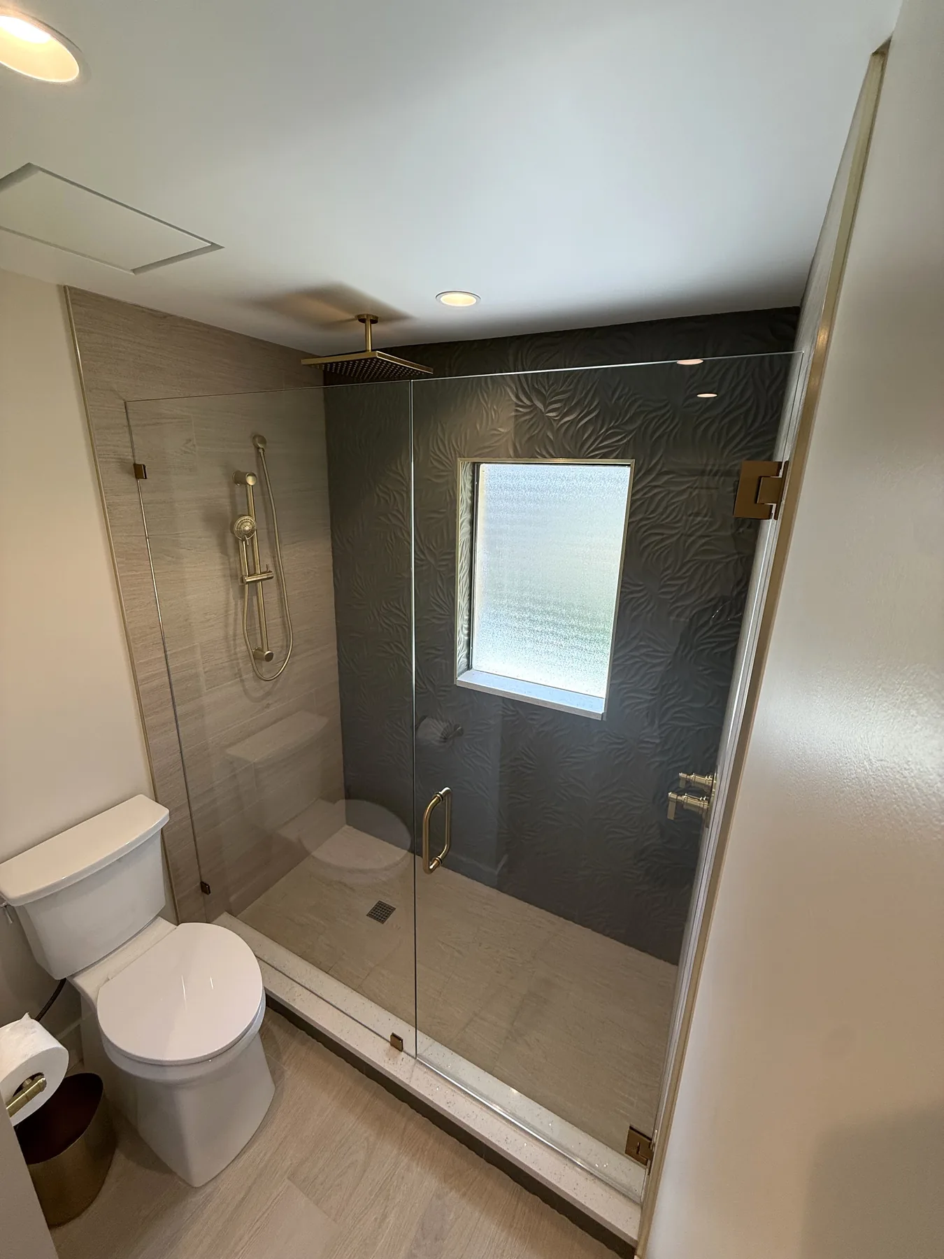 Walk-in shower remodel with frameless glass, large-format tile and brass fixtures in Central Florida