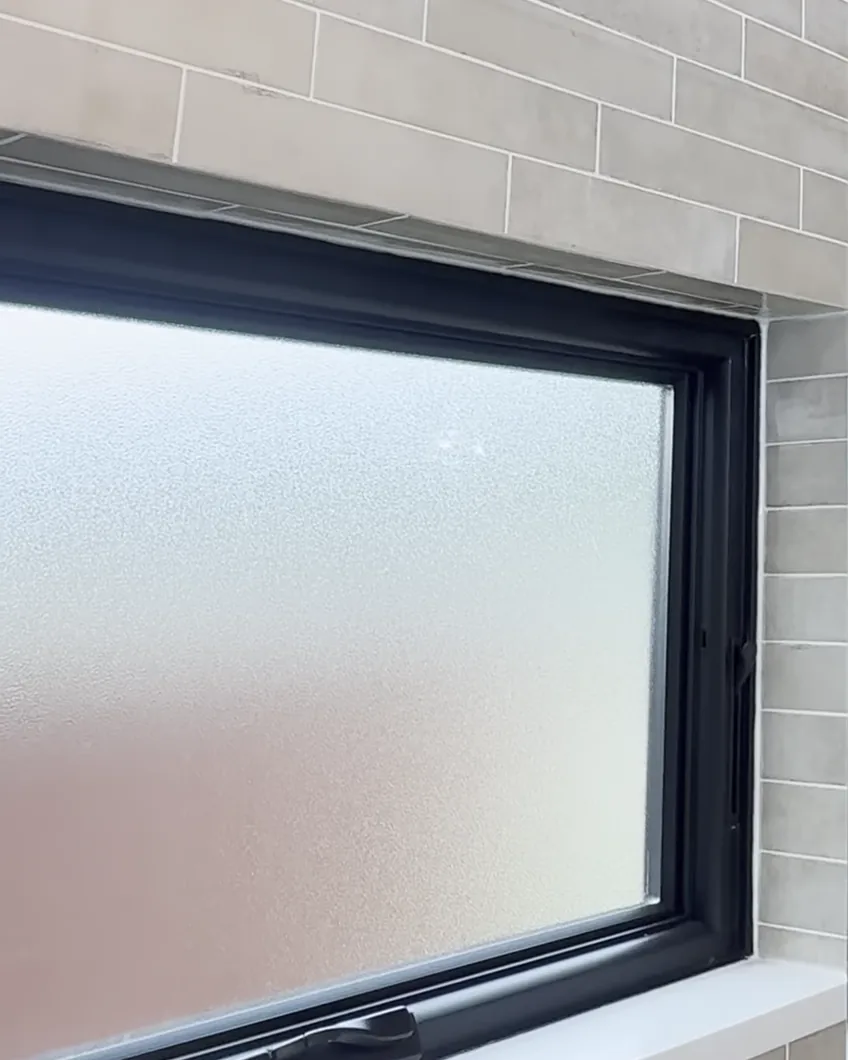 Window inside a walk-in shower with a matching quartz sill and tan tile in a Dr. Phillips, Orlando bathroom remodel