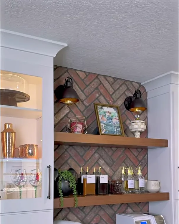 Coffee bar in a Winter Garden, FL kitchen remodel with a brick herringbone backsplash, floating wood shelves, sconces and glass-front cabinets