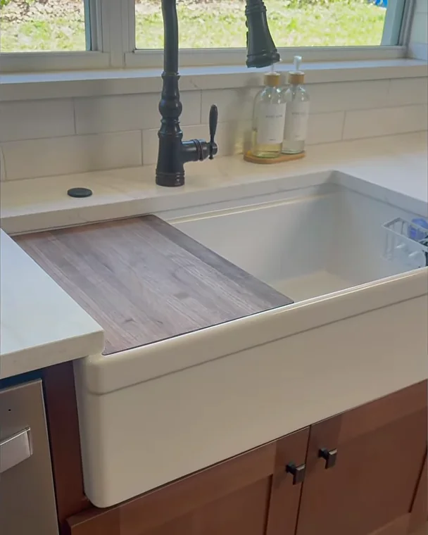 Apron-front workstation farm sink with a sliding cutting board and matte black faucet in a Winter Garden, FL kitchen remodel