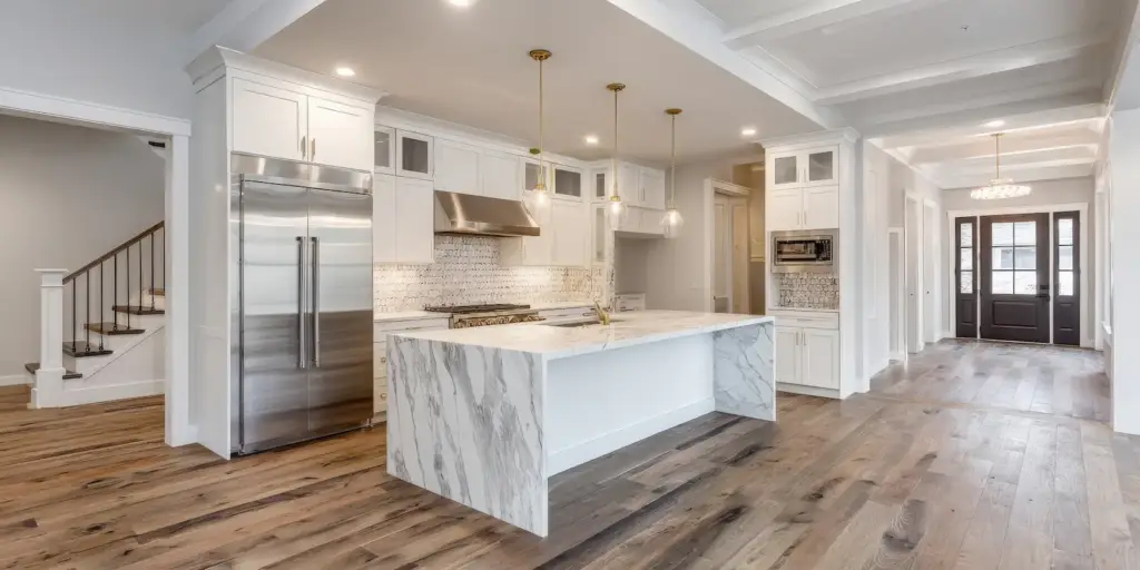 luxury kitchen remodel with white cabinets, marble island, and wood flooring