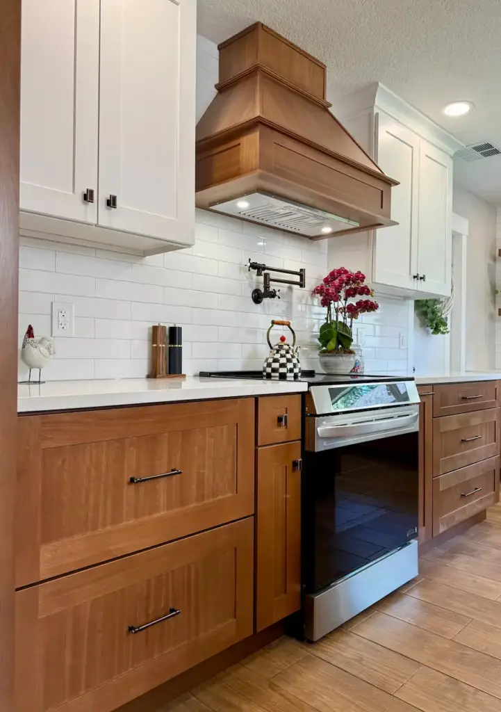 Custom kitchen remodel in Winter Park, FL with wood cabinetry, white backsplash, and custom wood range hood