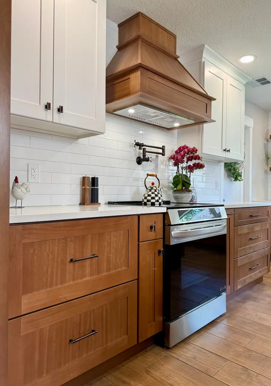 Kitchen remodeling in Davenport FL with white cabinets, wood range hood, and subway tile backsplash