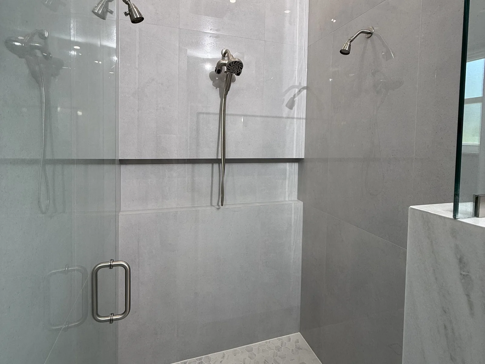 Walk-in shower remodel with large-format tile, frameless glass and a rain shower head by Posada Remodeling & Design